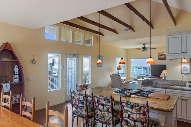 dining room featuring dark hardwood / wood-style floors, ceiling fan, sink, and lofted ceiling with beams