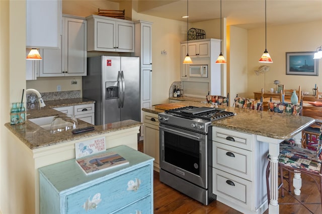 kitchen featuring a breakfast bar, sink, hanging light fixtures, appliances with stainless steel finishes, and kitchen peninsula