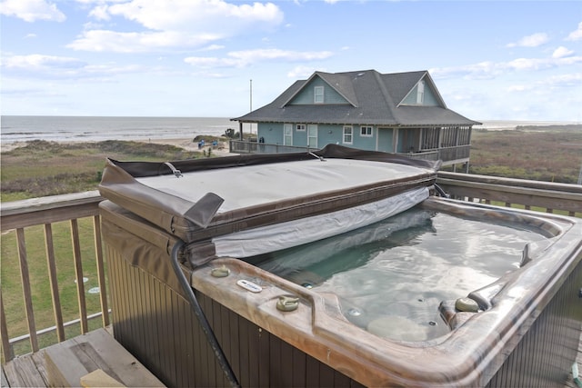 exterior space with a water view, a view of the beach, and a hot tub