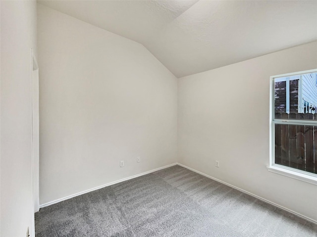 carpeted empty room featuring vaulted ceiling