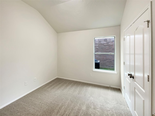 carpeted spare room featuring a healthy amount of sunlight and lofted ceiling