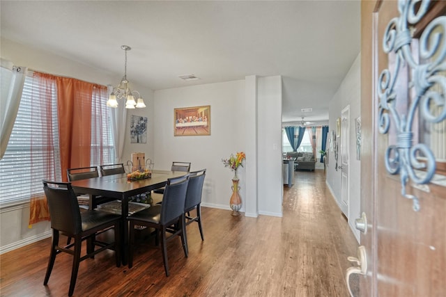 dining space with ceiling fan with notable chandelier and dark hardwood / wood-style floors