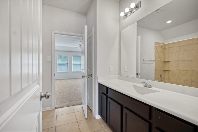 bathroom featuring tile patterned flooring, ceiling fan, tiled shower, and vanity