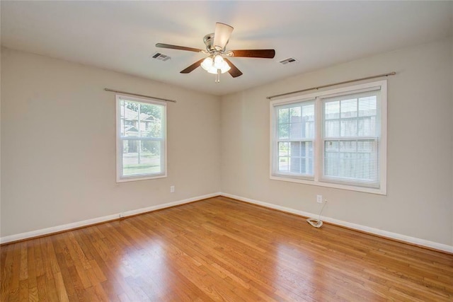 spare room featuring light hardwood / wood-style floors, ceiling fan, and a healthy amount of sunlight