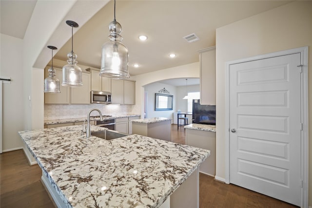 kitchen featuring hanging light fixtures, a center island with sink, dark hardwood / wood-style floors, and sink