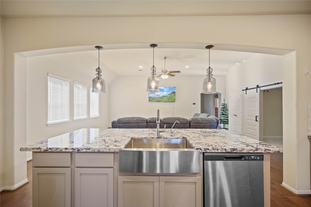 kitchen featuring ceiling fan, sink, a barn door, stainless steel dishwasher, and dark hardwood / wood-style floors