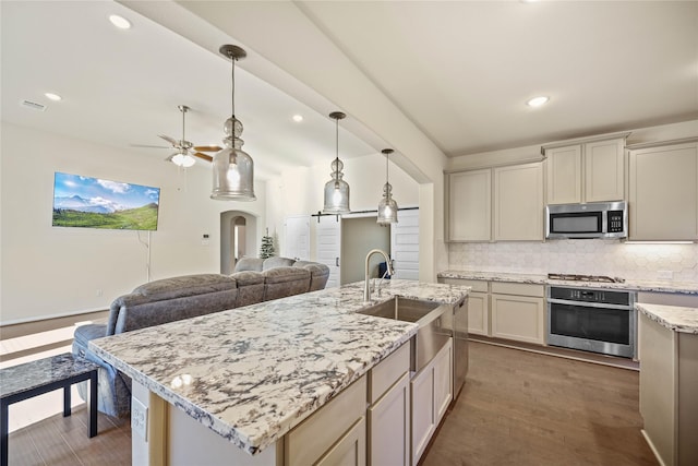 kitchen with sink, stainless steel appliances, tasteful backsplash, dark hardwood / wood-style floors, and a center island with sink