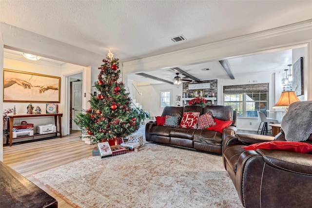 living room featuring plenty of natural light, beamed ceiling, a textured ceiling, and light wood-type flooring