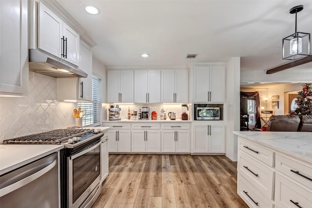 kitchen featuring white cabinets, decorative light fixtures, stainless steel appliances, and tasteful backsplash