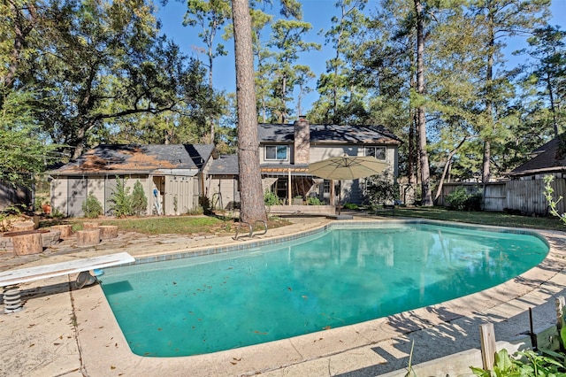 view of pool with a patio and a diving board