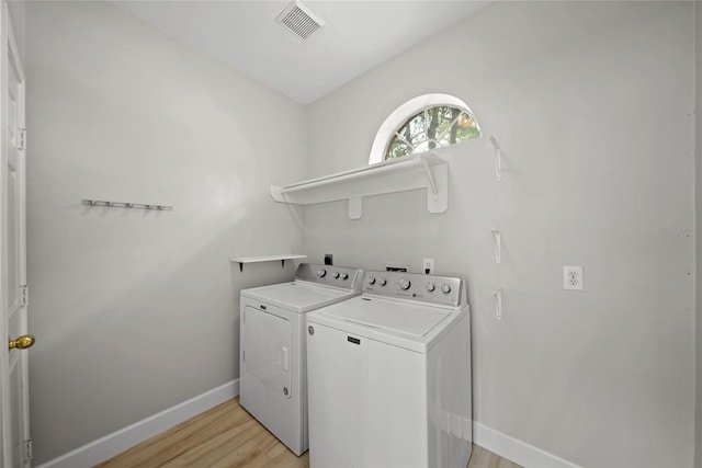 washroom featuring washing machine and clothes dryer and light hardwood / wood-style flooring