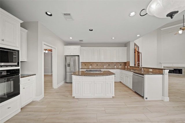 kitchen with a kitchen island, kitchen peninsula, decorative backsplash, sink, and stainless steel appliances