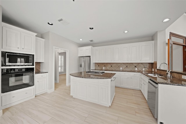 kitchen featuring a center island, stainless steel appliances, dark stone countertops, decorative backsplash, and sink