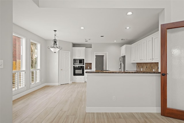 kitchen featuring decorative backsplash, white cabinets, oven, and built in microwave