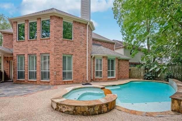 back of house featuring a swimming pool with hot tub and a patio