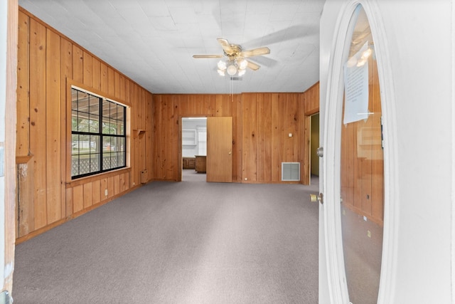 spare room with carpet, ceiling fan, and wooden walls