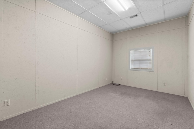 spare room featuring a paneled ceiling and light colored carpet