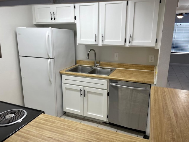 kitchen featuring stainless steel dishwasher, sink, white fridge, white cabinetry, and light tile patterned flooring