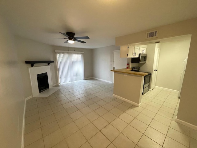 kitchen with white cabinetry, ceiling fan, kitchen peninsula, light tile patterned floors, and appliances with stainless steel finishes