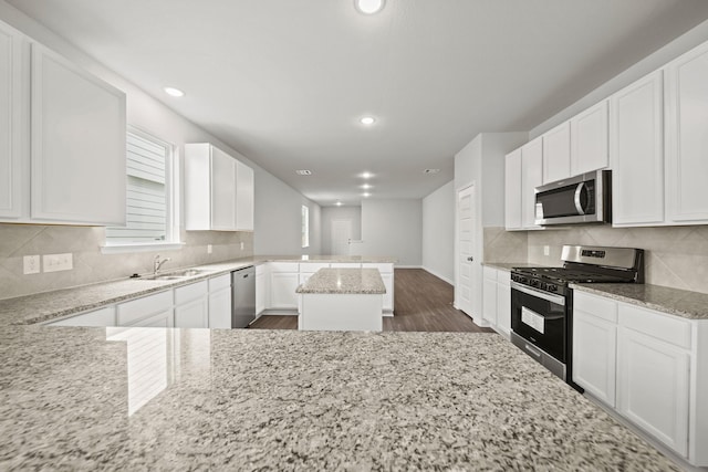 kitchen featuring white cabinetry, a kitchen island, light stone counters, and stainless steel appliances