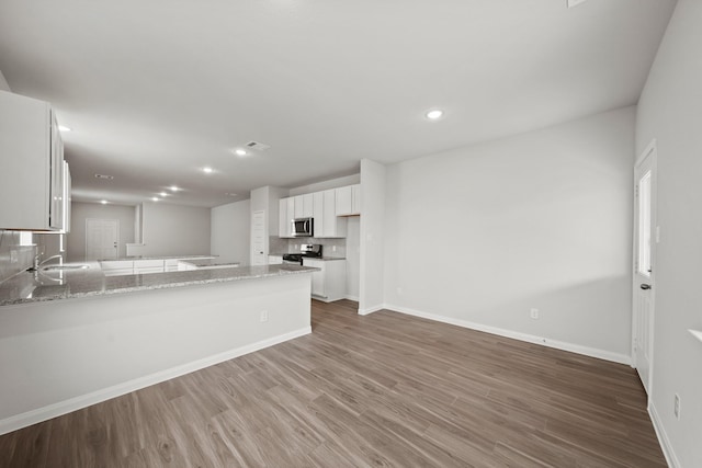 kitchen featuring a peninsula, light stone countertops, white cabinetry, and stainless steel appliances