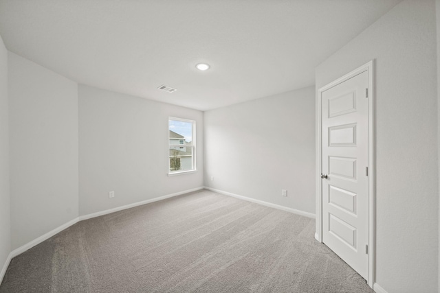 spare room featuring carpet, visible vents, and baseboards