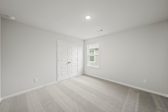 unfurnished bedroom featuring baseboards, a closet, visible vents, and light colored carpet