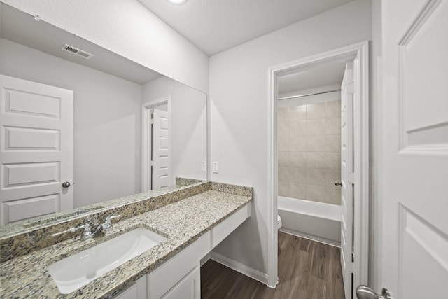 full bathroom featuring visible vents, toilet, tub / shower combination, vanity, and wood finished floors