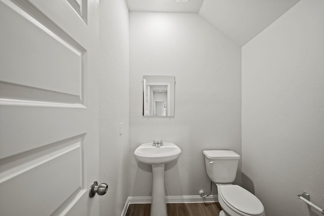 bathroom with toilet, baseboards, wood finished floors, and lofted ceiling