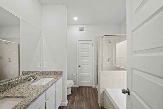 full bathroom featuring double vanity, visible vents, toilet, wood finished floors, and a sink