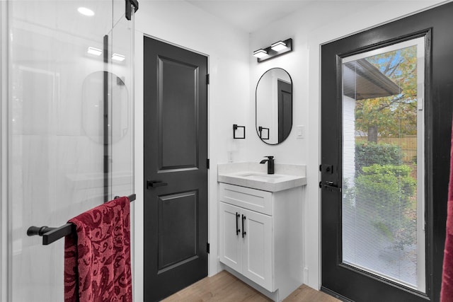 bathroom with hardwood / wood-style floors, vanity, and a shower