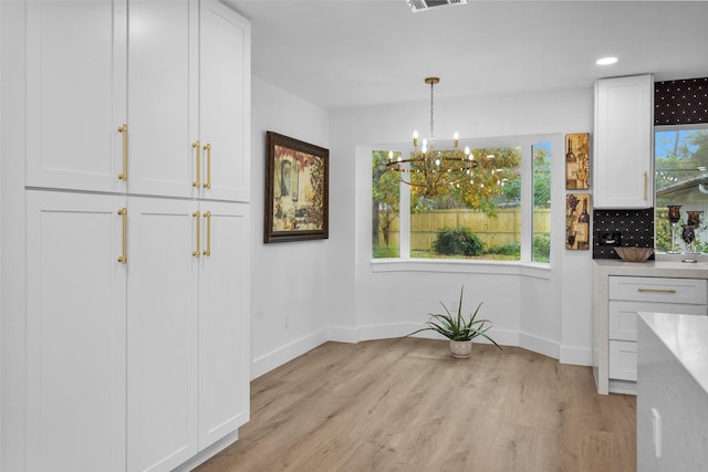 unfurnished dining area featuring a notable chandelier and light wood-type flooring