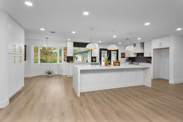 kitchen with custom range hood, a spacious island, light hardwood / wood-style flooring, white cabinetry, and hanging light fixtures