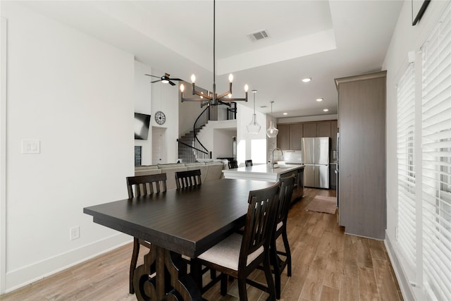 dining area with an inviting chandelier, a wealth of natural light, sink, and light wood-type flooring