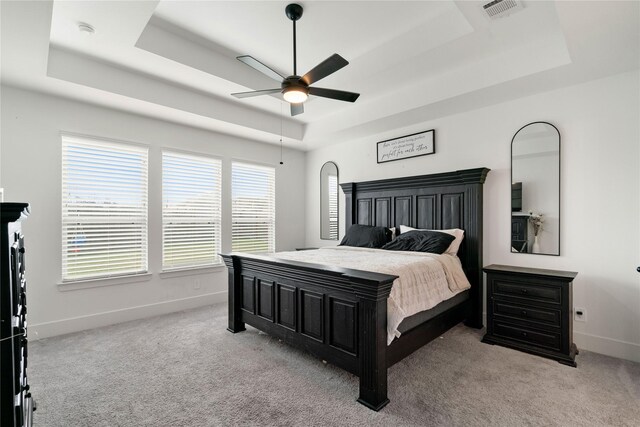 carpeted bedroom with a raised ceiling and ceiling fan