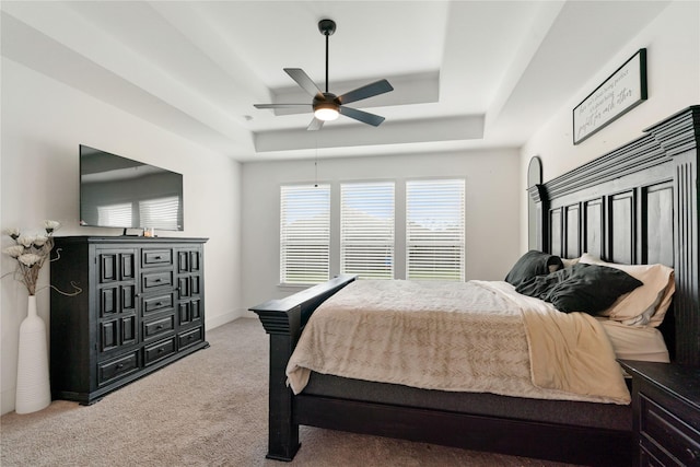 bedroom with ceiling fan, a tray ceiling, and carpet floors