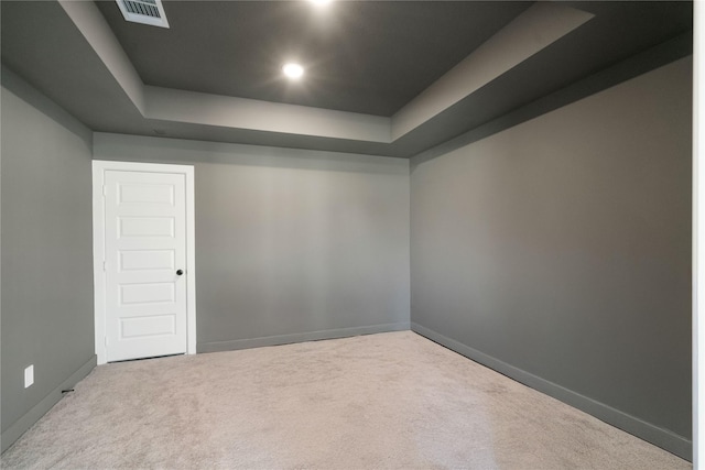 spare room with a tray ceiling and light carpet