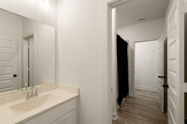 full bath with visible vents, wood finished floors, vanity, and baseboards