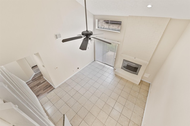 unfurnished living room with ceiling fan, a large fireplace, light hardwood / wood-style floors, and vaulted ceiling