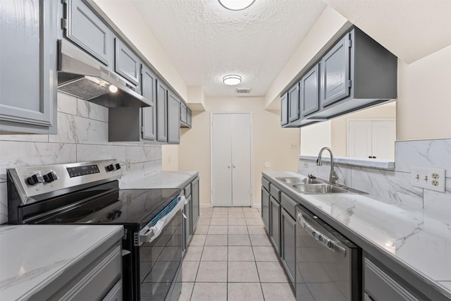 kitchen featuring gray cabinetry, sink, a textured ceiling, light tile patterned flooring, and appliances with stainless steel finishes