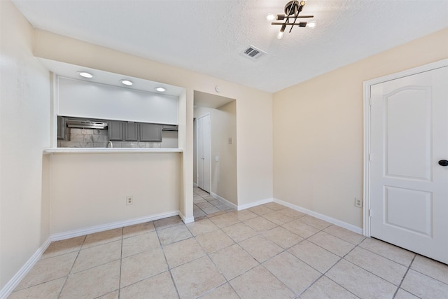 tiled empty room with a textured ceiling