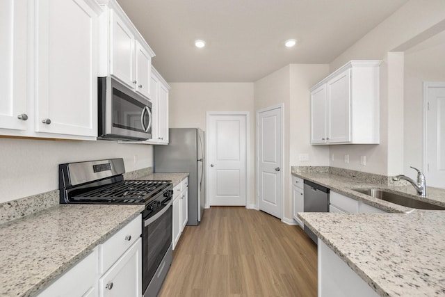 kitchen featuring light stone countertops, appliances with stainless steel finishes, white cabinetry, and sink