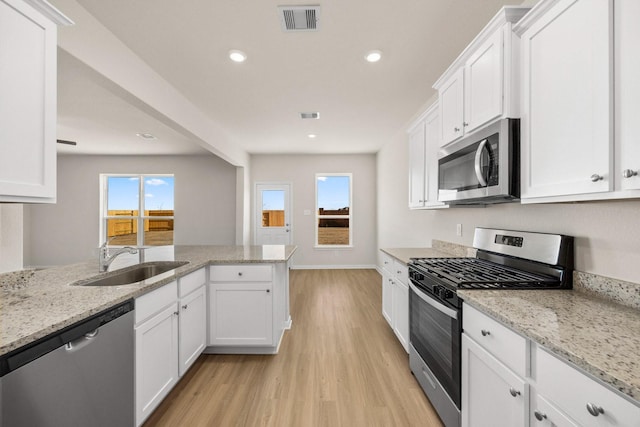 kitchen featuring light stone countertops, stainless steel appliances, sink, light hardwood / wood-style flooring, and white cabinetry