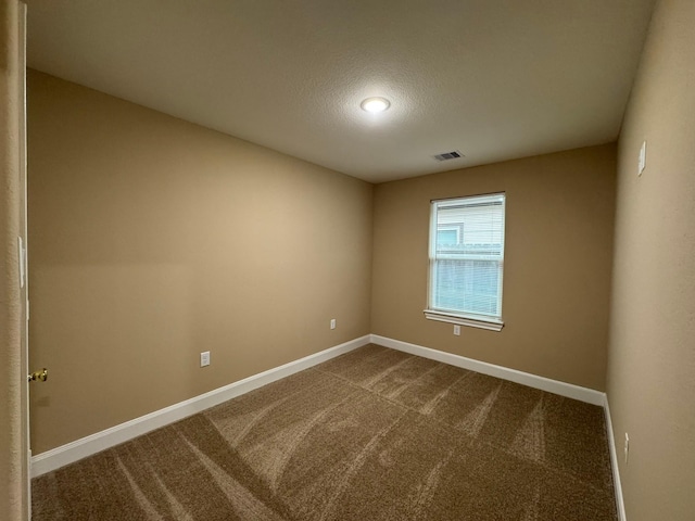 spare room featuring carpet and a textured ceiling