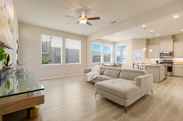 living room with ceiling fan, light hardwood / wood-style flooring, a healthy amount of sunlight, and sink