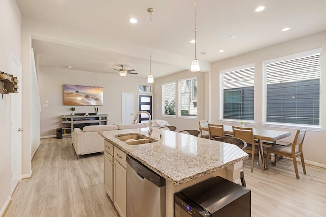 kitchen featuring a kitchen island with sink, ceiling fan, light stone counters, sink, and stainless steel dishwasher