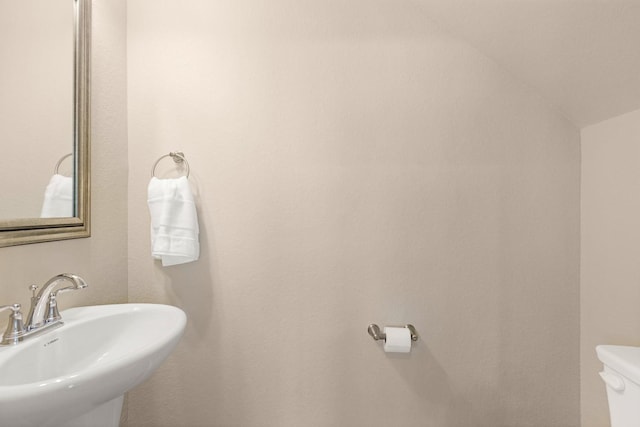 bathroom featuring lofted ceiling, toilet, and sink