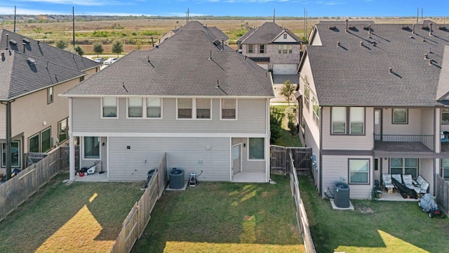 rear view of property featuring a lawn, central AC, and a patio area