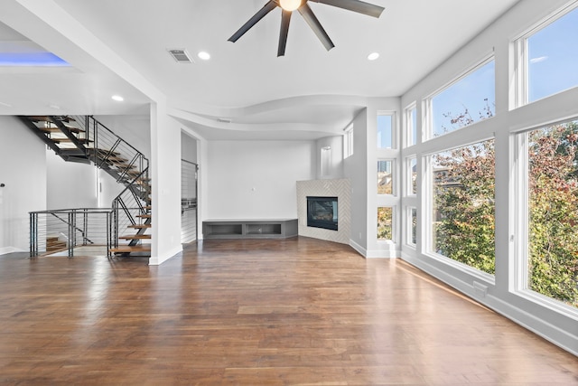 unfurnished living room with ceiling fan, a healthy amount of sunlight, and dark wood-type flooring