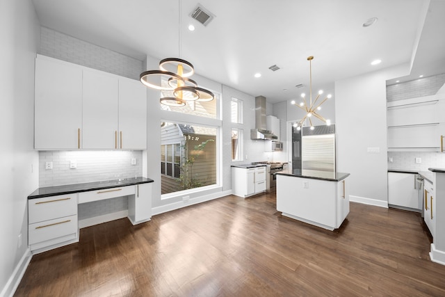 kitchen featuring white cabinets, decorative light fixtures, wall chimney exhaust hood, premium appliances, and a chandelier